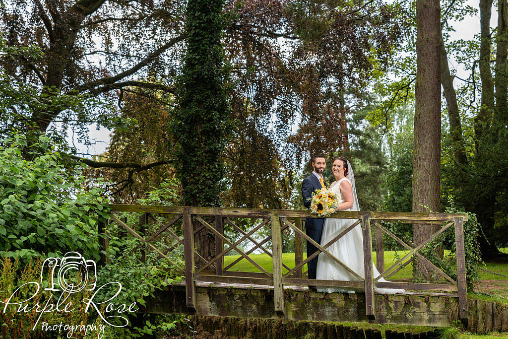 Bride and groom standing on a wooden bridge