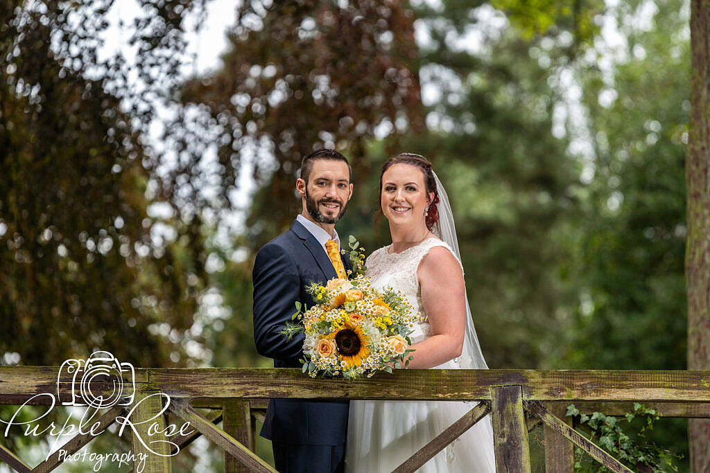Bride and groom smiling on a bridge