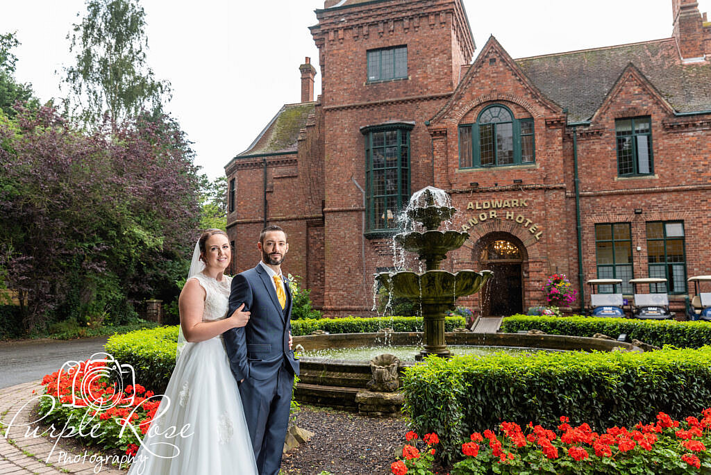 Bride and groom standing by a water fountain