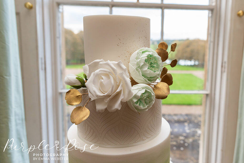 Gold, green and white flowers and foliage on a wedding cake in Kelmarsh Hall Northampton