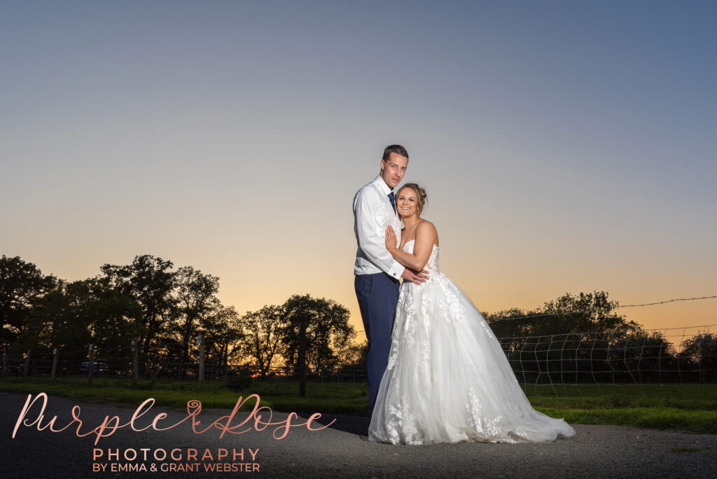 Bride and groom stood in front of a sunset on their wedding day in Milton Keynes