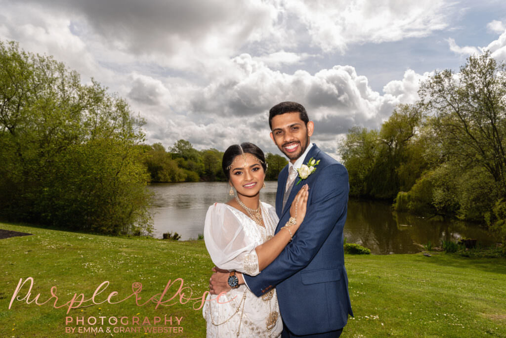 Photo of bride and groom in front of a lake on their wedding day in Milton Keynes