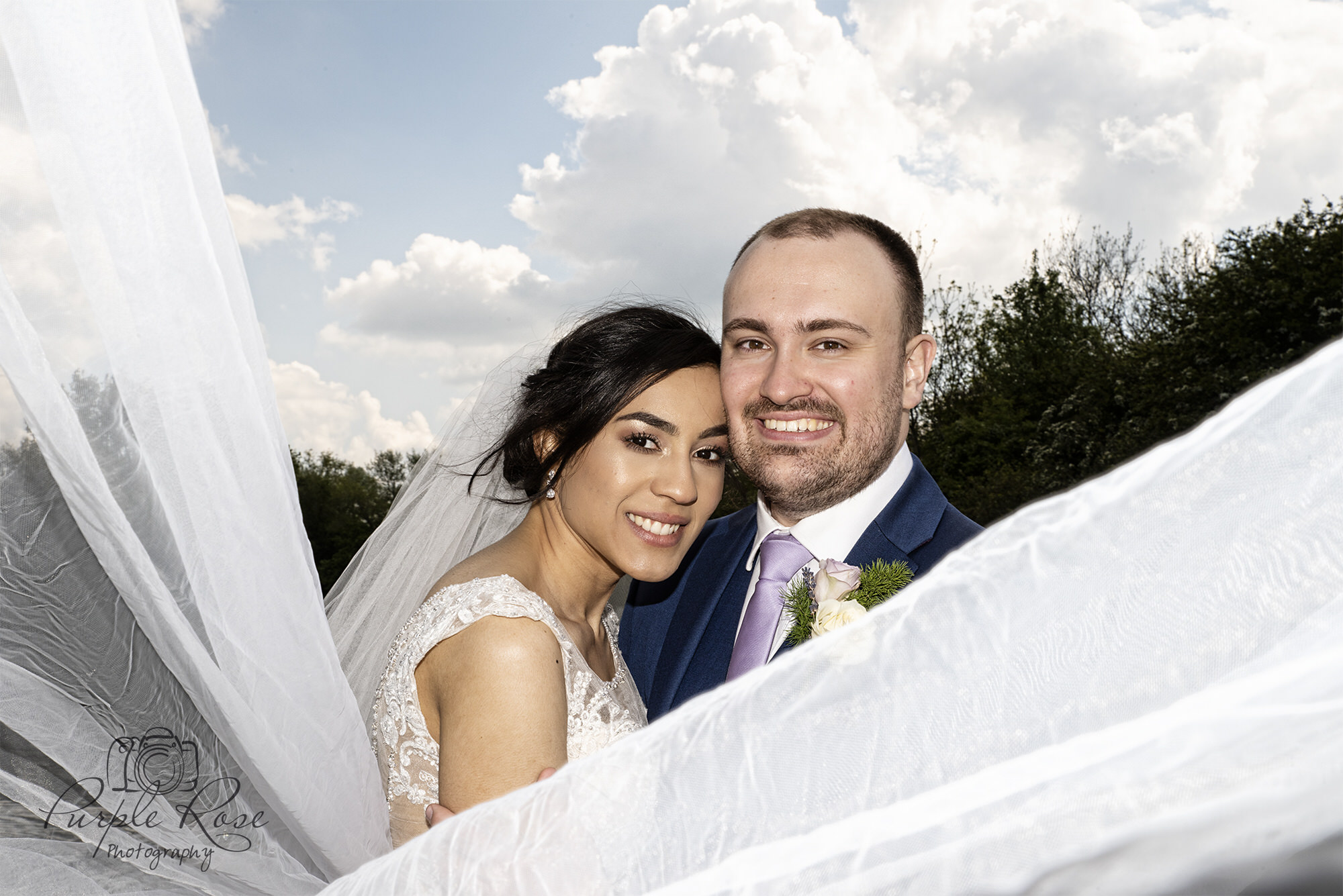 Bride and groom wrapped in brides wedding veil