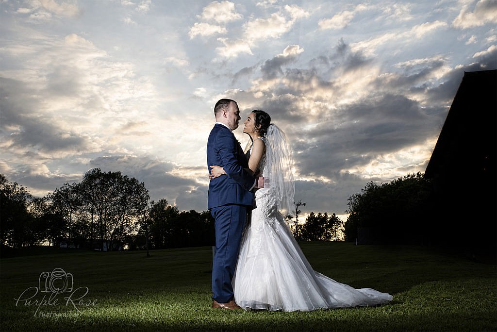 Bride & groom embracing in front of a dramatic sky