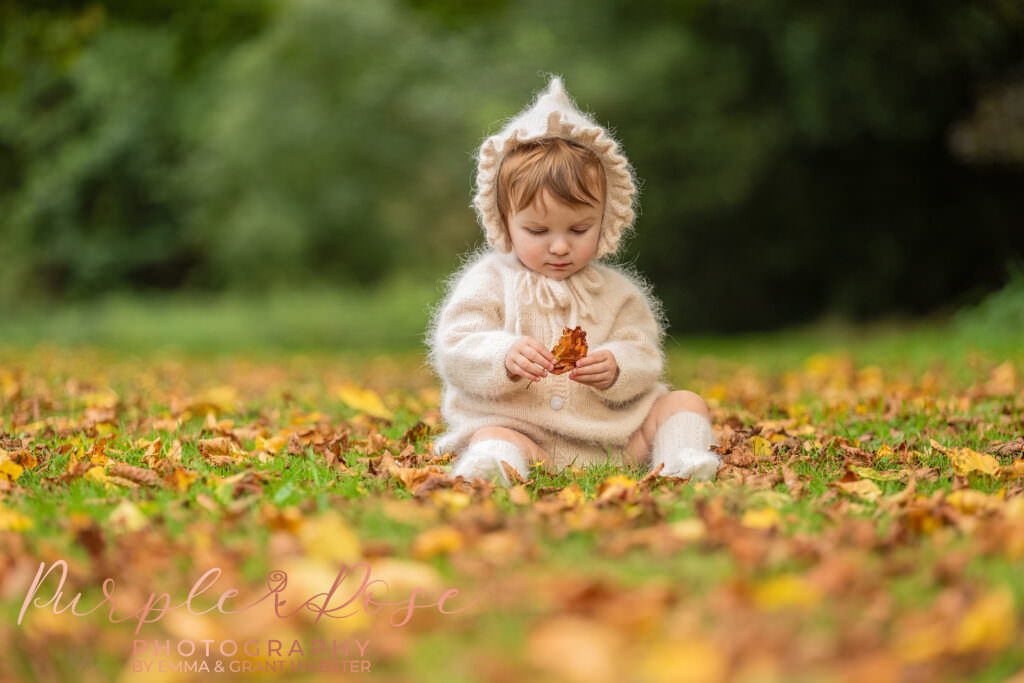 A girl sat amongst autumn leafs at a photo shoot in Milton Keynes