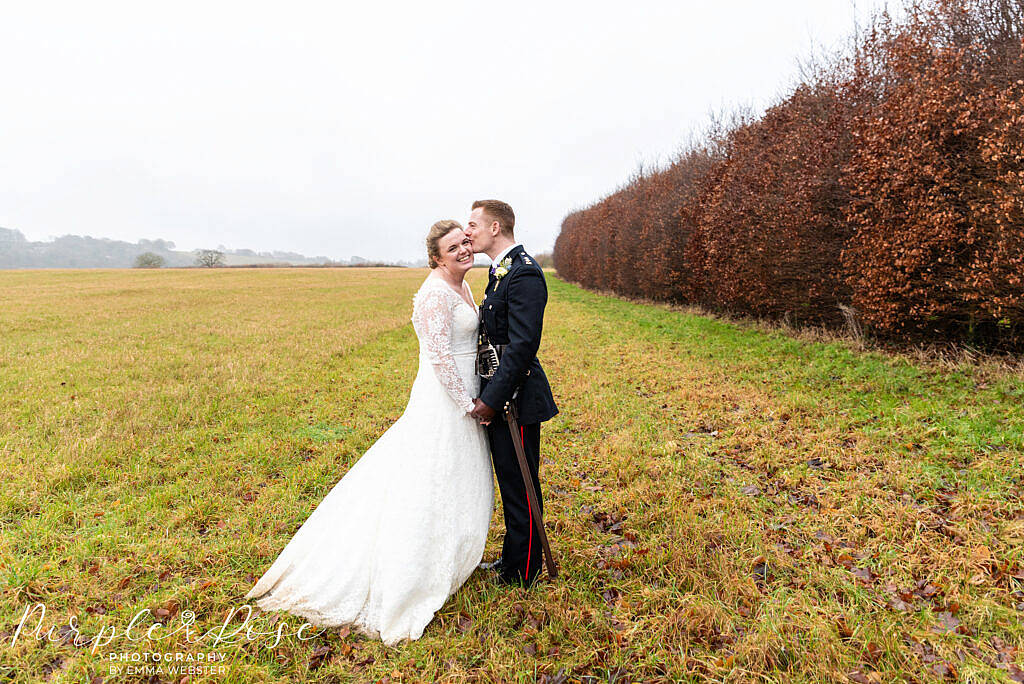 Groom kissing his bride in a field