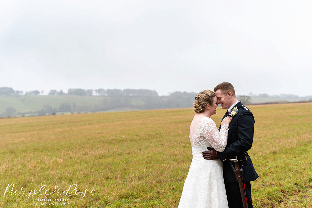 Bride and groom embracing in a field