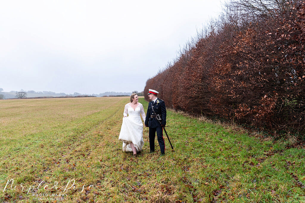 bride and groom walking through a field