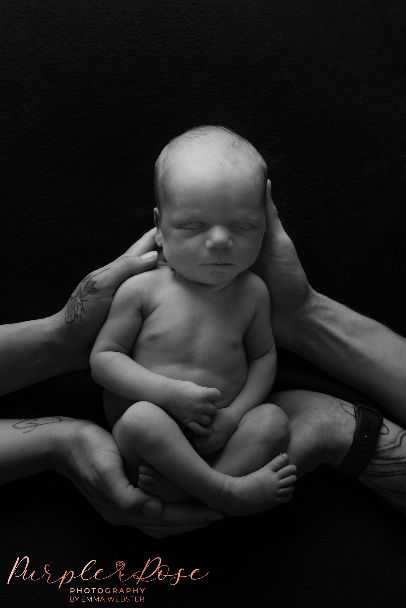 Mum and dads hands cradling baby