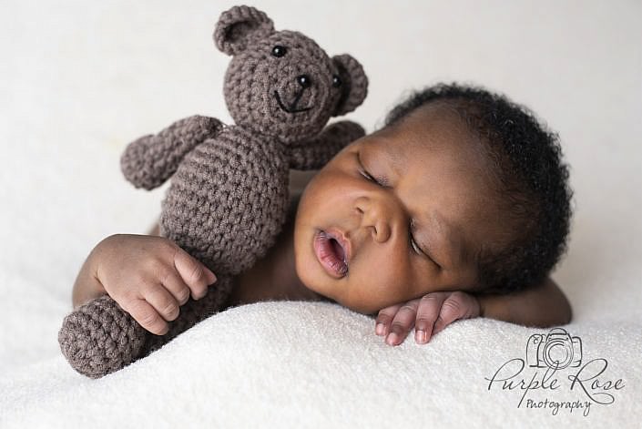 Baby sleeping while holding a teddy
