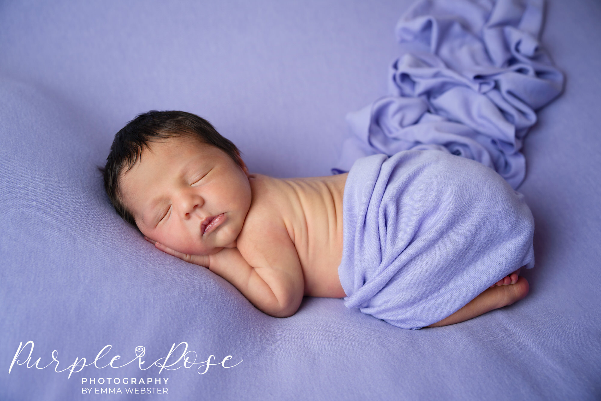 New born baby sleeping on a purple blanket