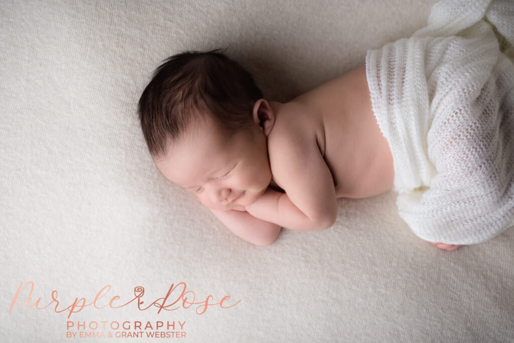 Photo of a newborn baby smiling whilst asleep during his newborn photoshoot in Milton Keynes