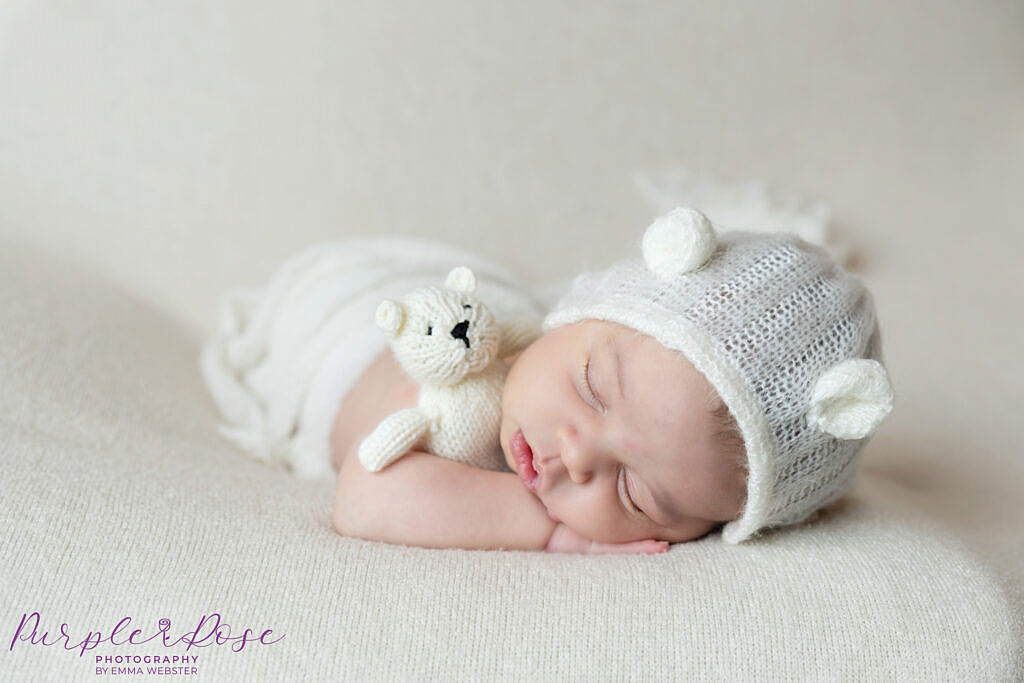 Baby girl cuddling teddy with bear bonnet on