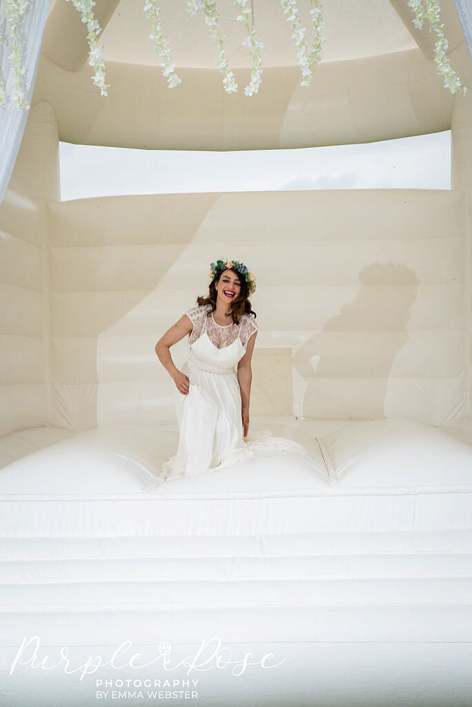 bride laughing on a bouncy castle