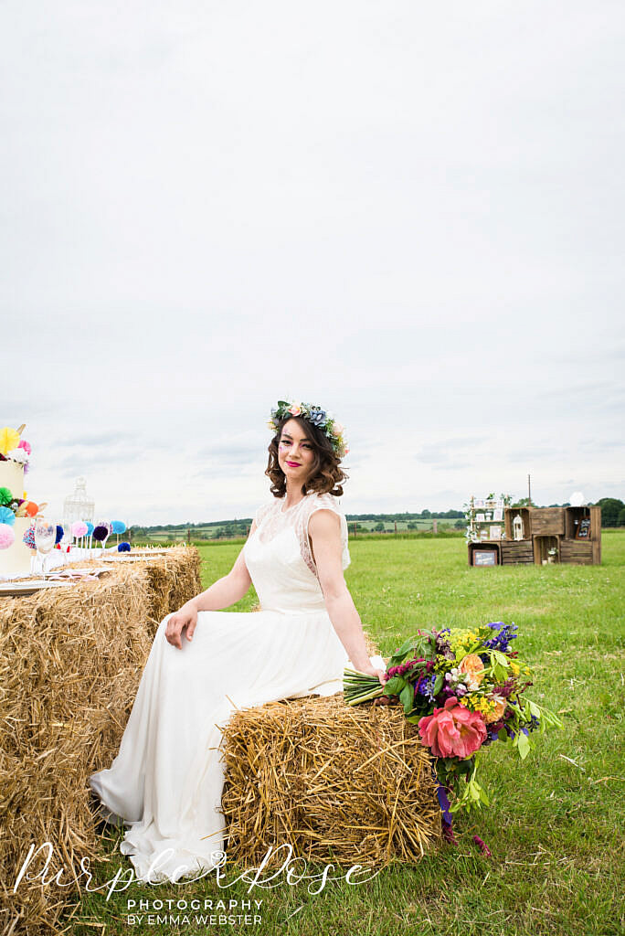 Bride sitting on a hay bale holding her flowers