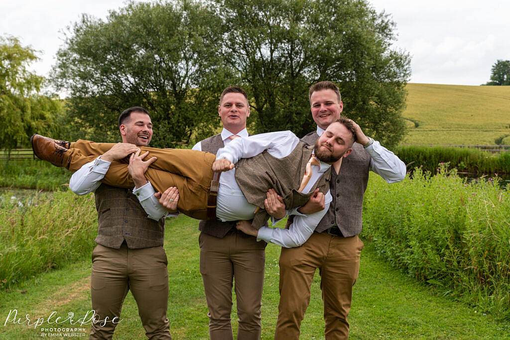 Groom being carried by his groomsmen