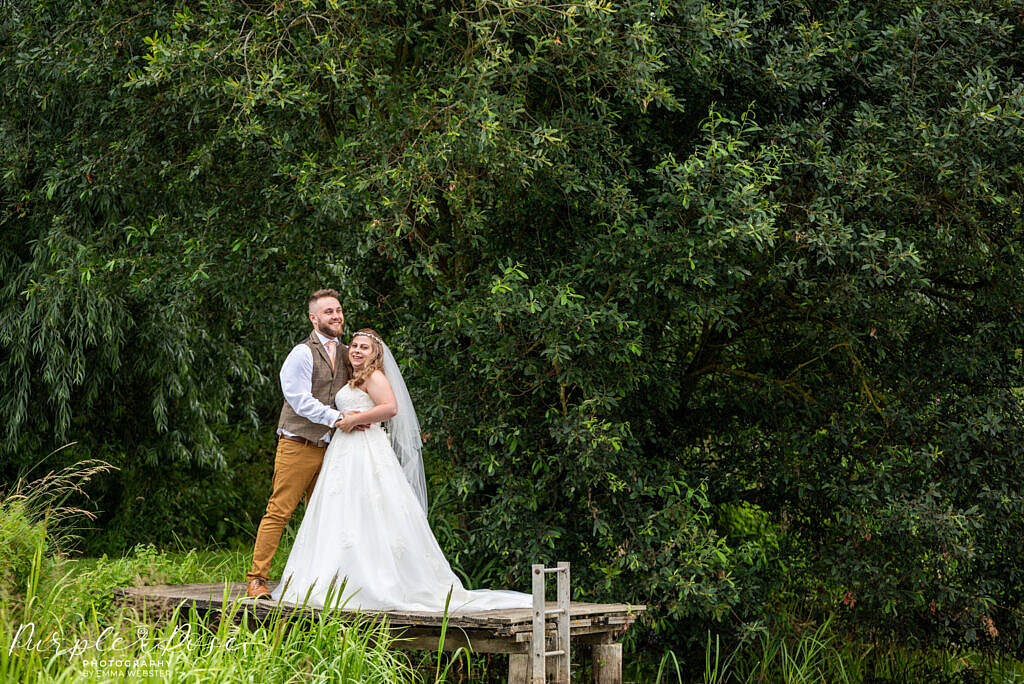 Bride and groom standing together by a lake