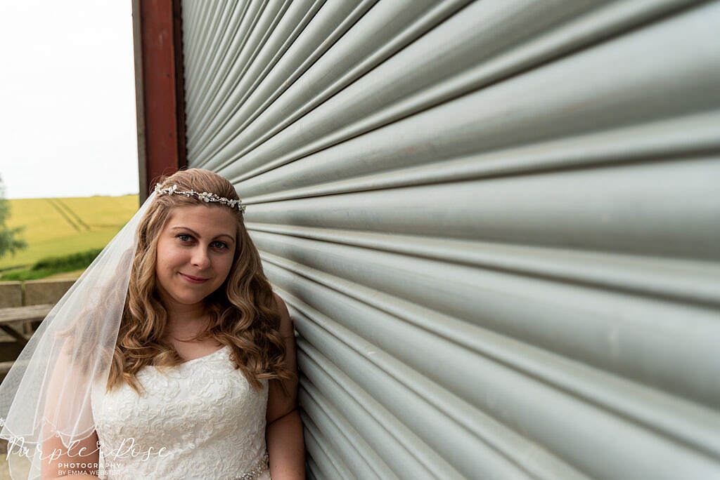 bride leaning on metal barn door