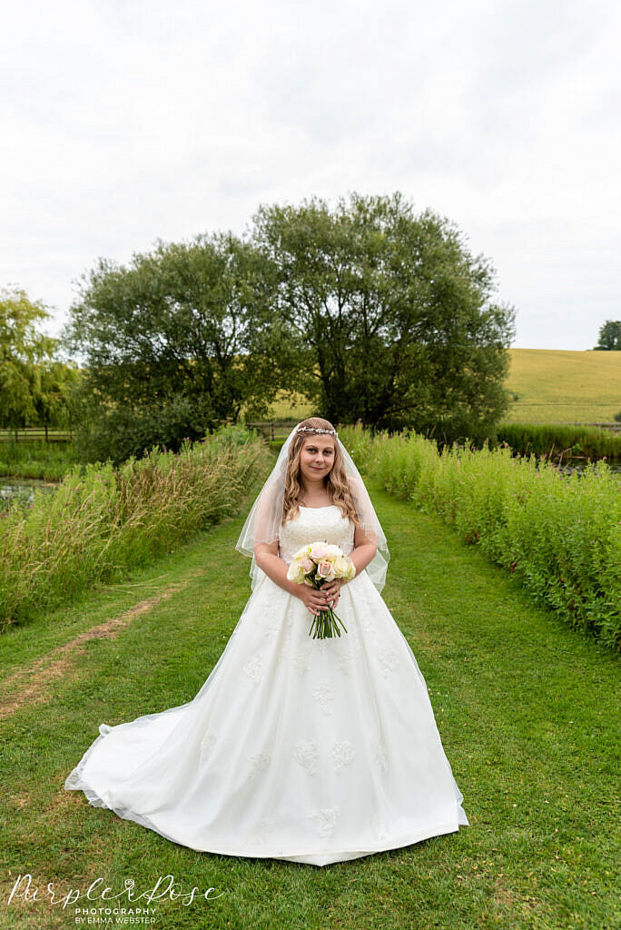 bride standing in venues gardens
