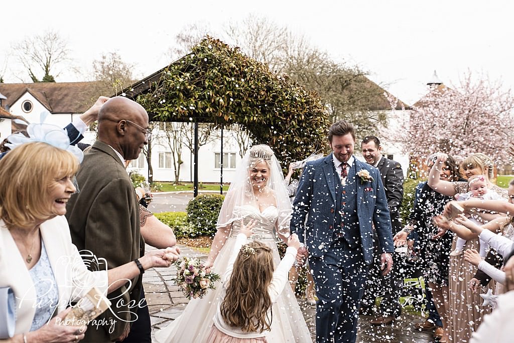 Bride and groom being showered in confetti