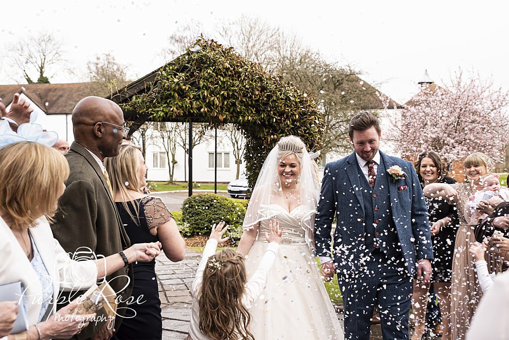 Bride and groom being showered in confetti