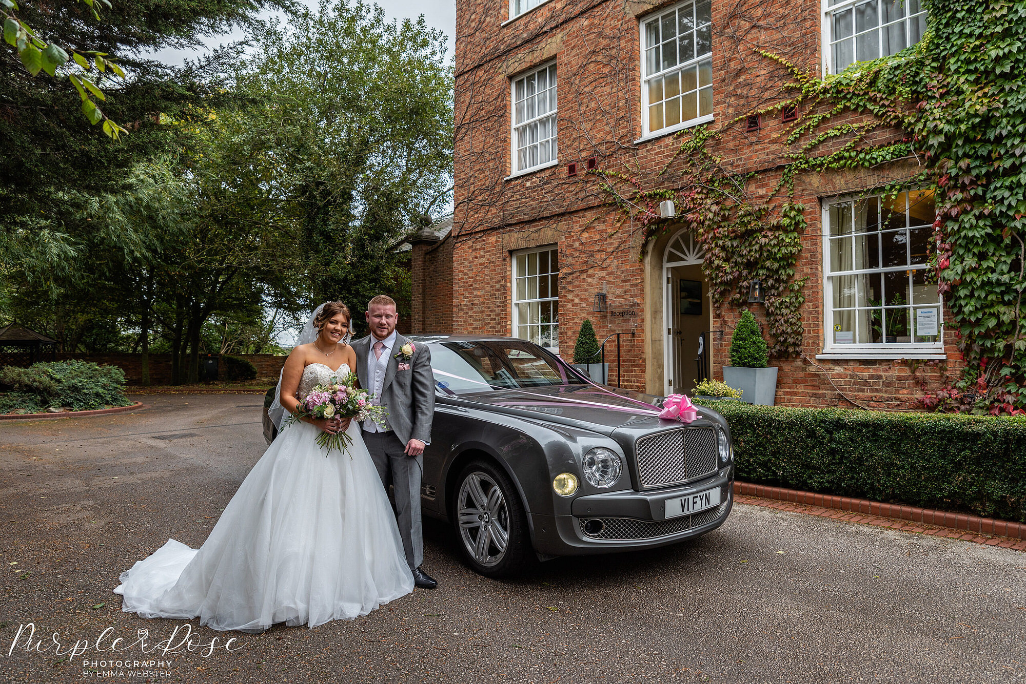 Photo of ride and groom by the wedding car in front of the wedding venue in Milton Keynes