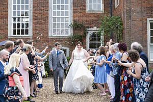 Bride and groom walking as confetti is thrown at them