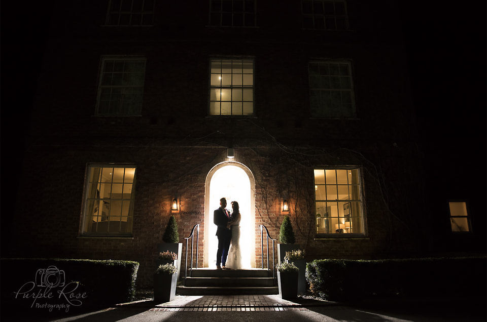 Night time photo of bride and groom in front of their venue