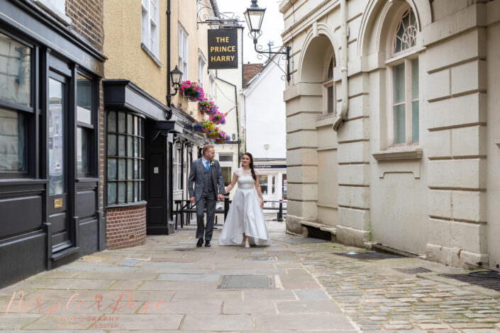 Bride and groom walking hand in hand down a cobbled street