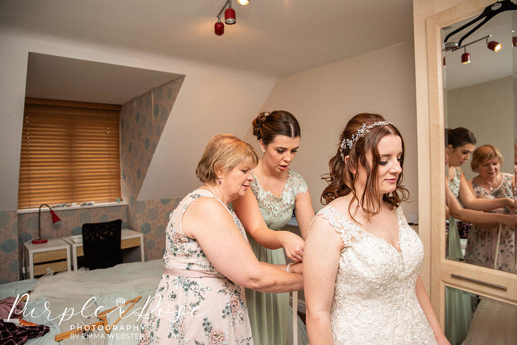 Brides family lacing her dress