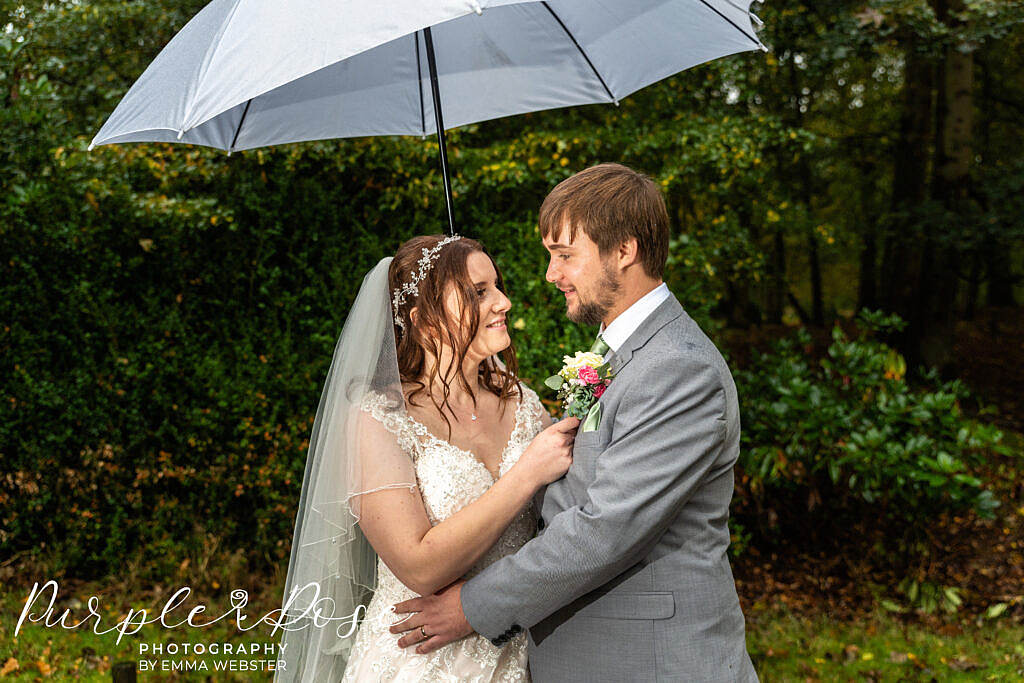 Bride and groom sheltering under an umbrella