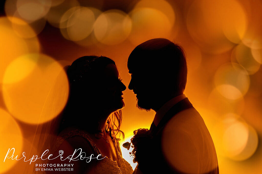 Siloueete of bride and groom surrounded by orange balls of light