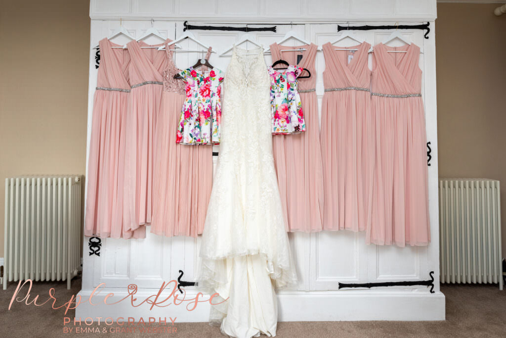 Photogrpah of wedding dress and bridesmaids dresses hung on a wardrobe in Chicheley hall  in Milton Keynes