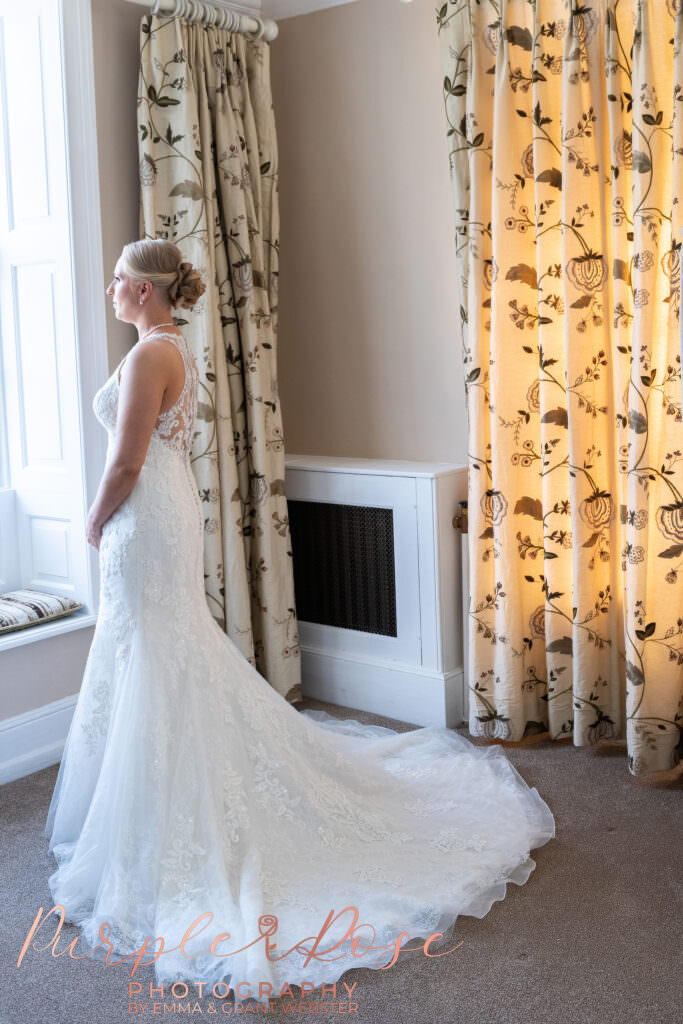 Photograph of a bride looking out a window on her wedding day in Milton Keynes