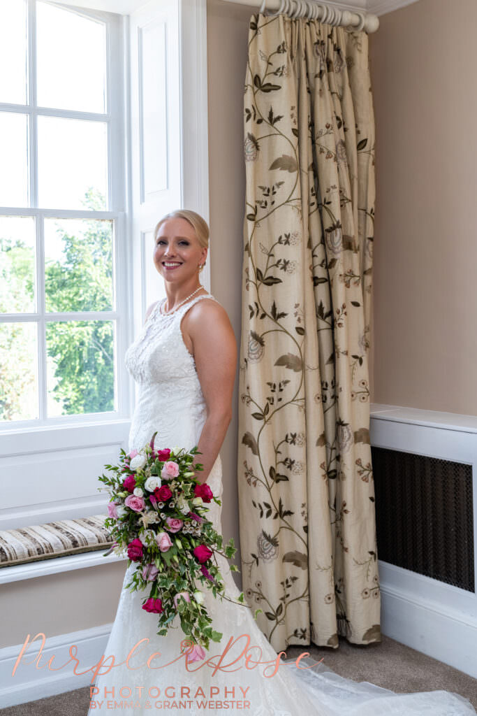 Photograph of bride stood by window on her wedding day at Chicheley Hall  in Milton Keynes