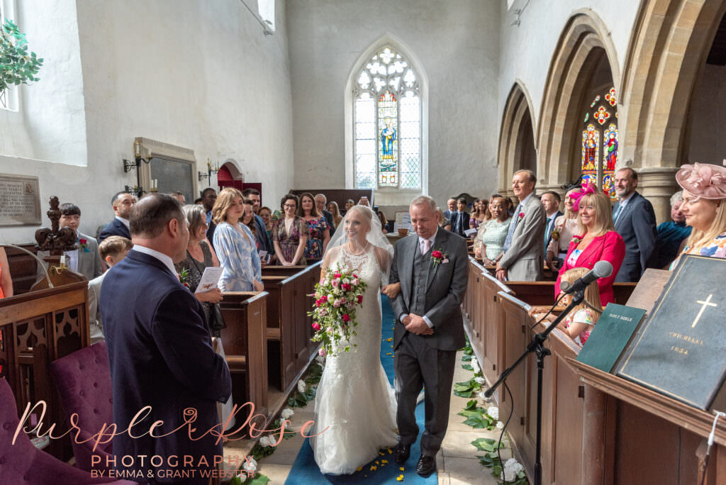 Photograph of bride and her father walking into church on her wedding day  in Milton Keynes