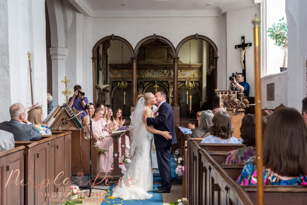 Photograph of bride and groom kissing at the end of their wedding ceremony in Chicheley Church  in Milton Keynes