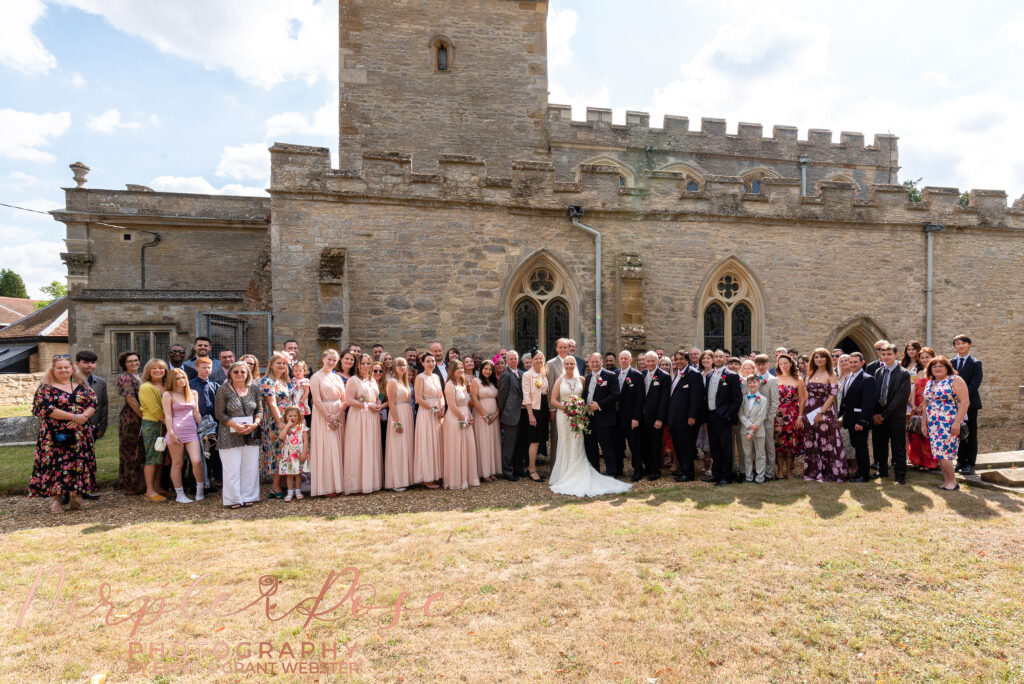 Group photo of wedding guests outside Chicheley Church  in Milton Keynes