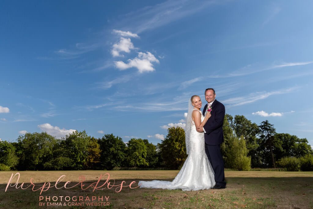 Bride and groom stood on grass outside their wedding venue at a photoshoot in Milton Keynes