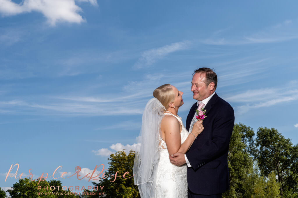 Photograph of a bride and groom in front of a blue sky on ther wedding day at Chicheley Hall  in Milton Keynes