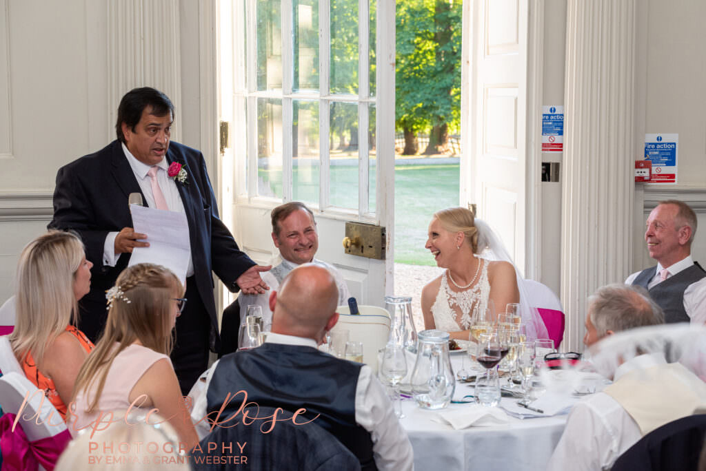 Bride and groom laughing during the best mans speech on their wedding day  in Milton Keynes