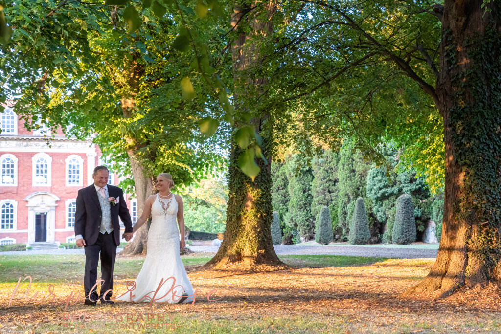 Photograph of a bride and groom walking hand in had during golden hour in Milton Keynes on their wedding day  in Milton Keynes