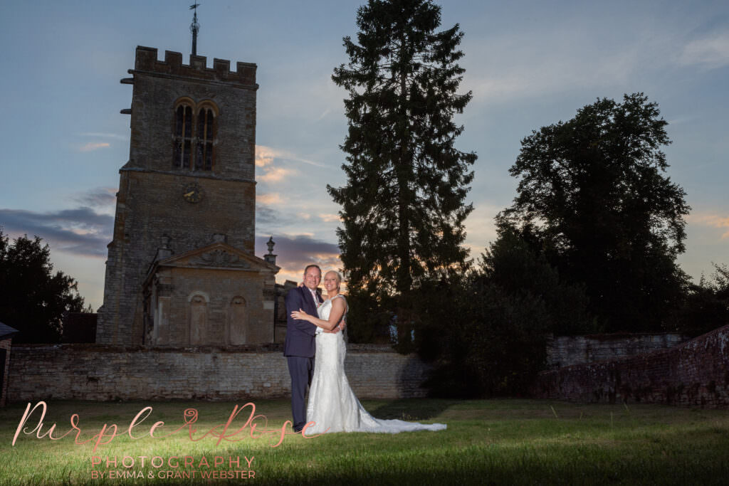 Photograph of a bride and groom at sunset in front of the church they were married at in Milton Keynes