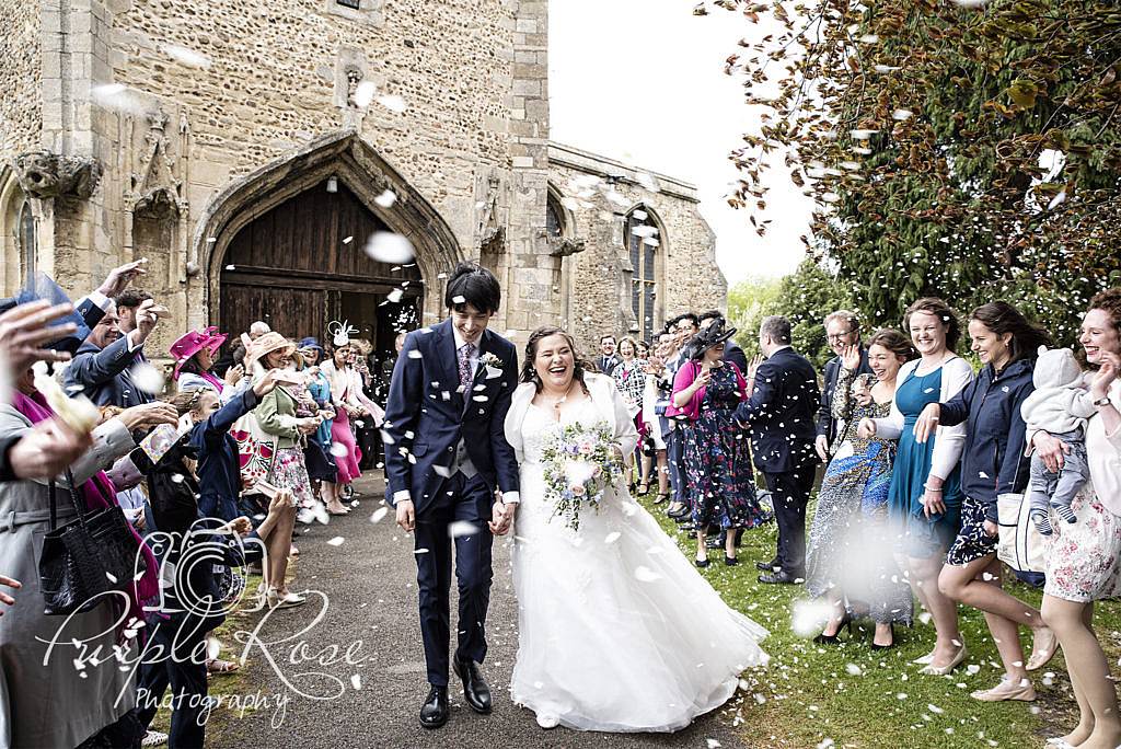 Bride and Groom being showered in confetti as they leave the church