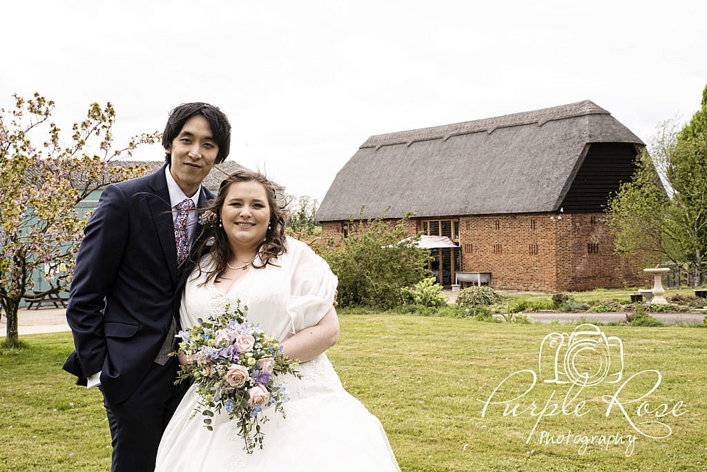 Bride and groom stood in front of their barn wedding venue