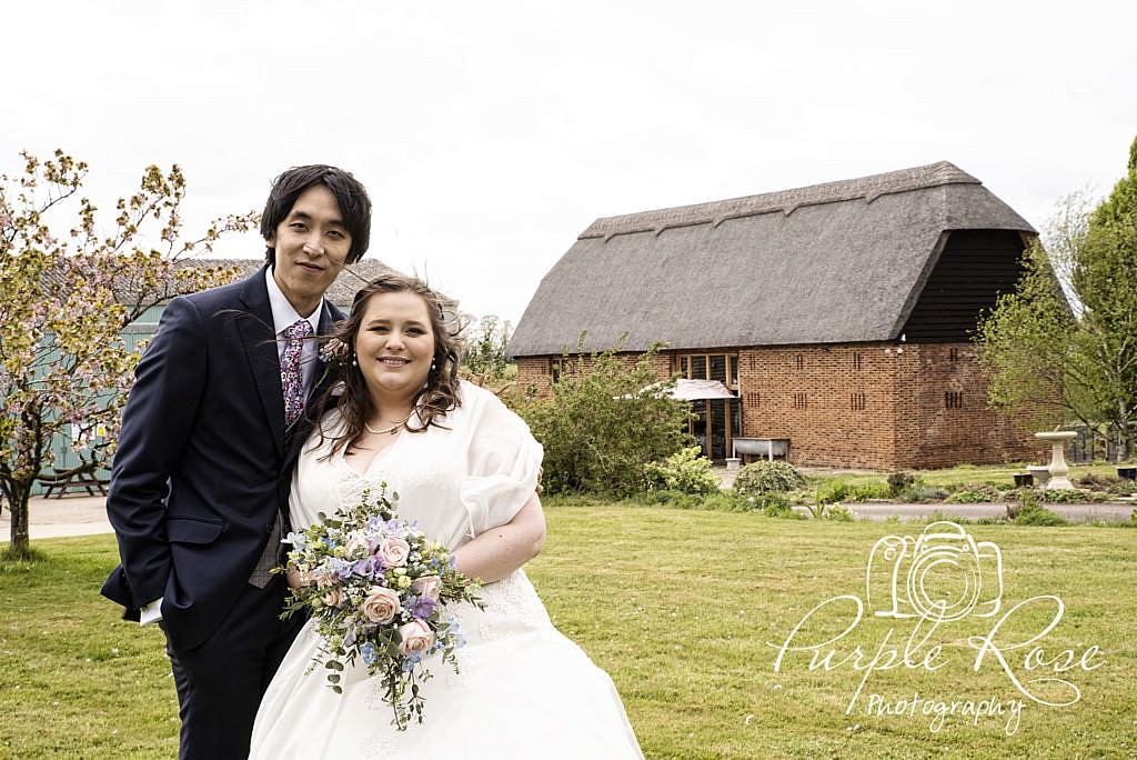 Bride and Groom standing in front of the Thatched Barn