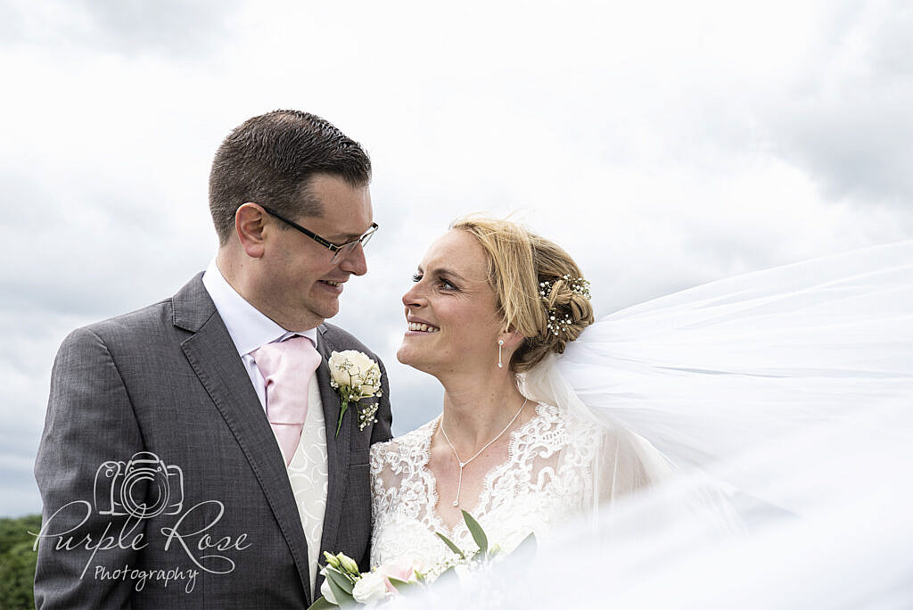 Wedding veil swirling round a bride and groom