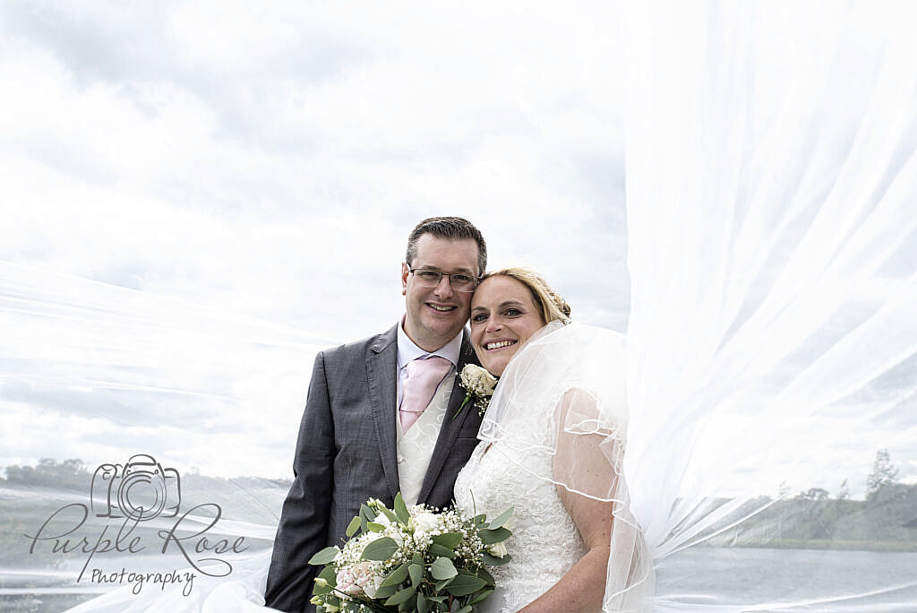 bride and groom in front of a cloudy sky