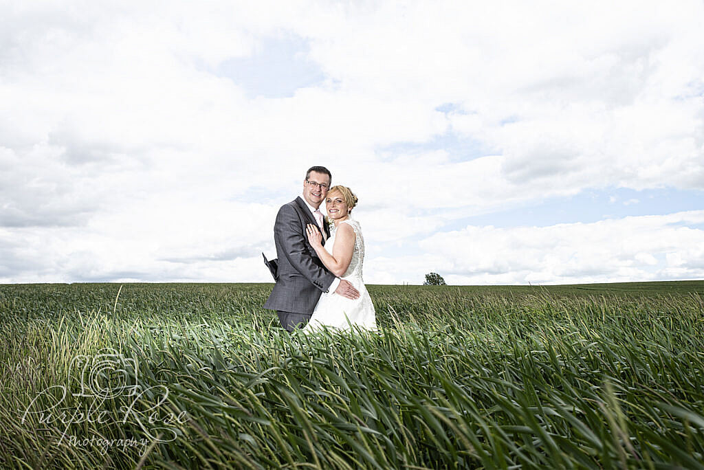 Bride and groom embracing on a field