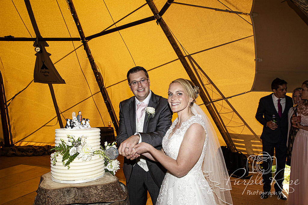 bride and groom cutting their cake in a tipi